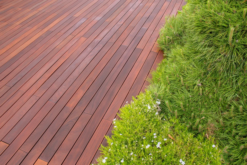 Terrasse extérieure couverte par une pergola bioclimatique à lames orientables en bois clair, structure en acier laqué anthracite